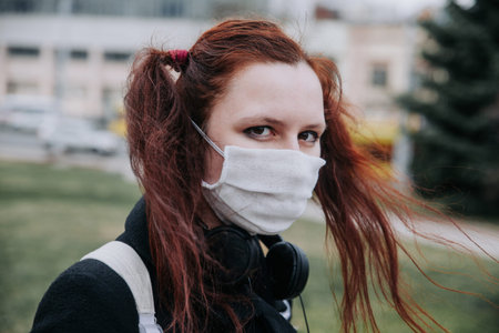 Woman with a medical face mask in park outdoor . Cold and flu.の写真素材