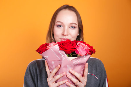pretty woman holding roses in hands on yellow background. Women's day concept. 8 march