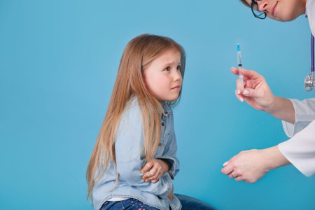 Frightened baby girl before an injection on blue studio backgroundの写真素材