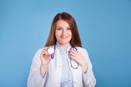 Portrait of confident young woman doctor on blue studio background.の写真素材