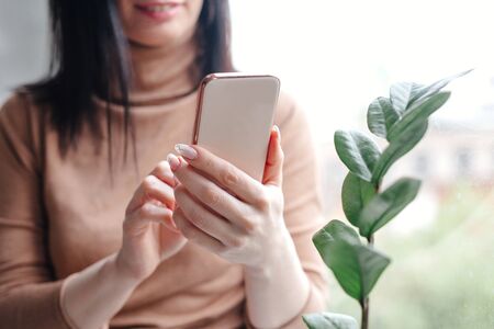 Close up young woman looking at smartphone for video online chat with friends or surf the internet or playing mobile application in relax timeの写真素材
