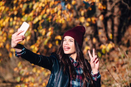 Stylish woman makes a selfie in autumn park.の写真素材