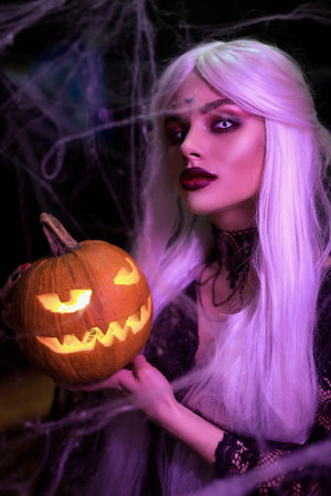 Mysterious Halloween witch woman portrait with pumpkin.
