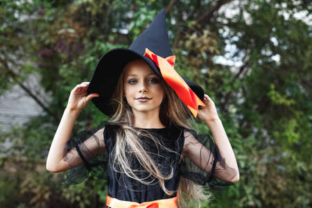 Little girl in witch costume outdoor. Happy Halloweenの写真素材