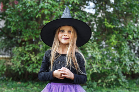 Beautiful young child girl in witch costume outdoors. Happy Halloweenの写真素材