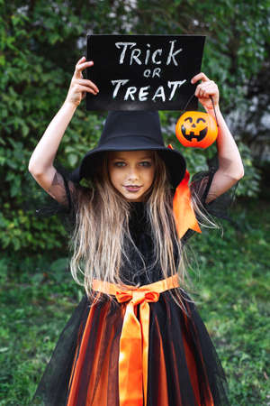 Little girl in witch costume trick or treating outdoor. Happy Halloweenの写真素材
