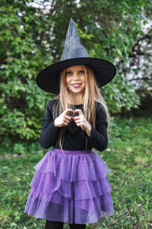 Beautiful young child girl in witch costume outdoors. Happy Halloweenの写真素材