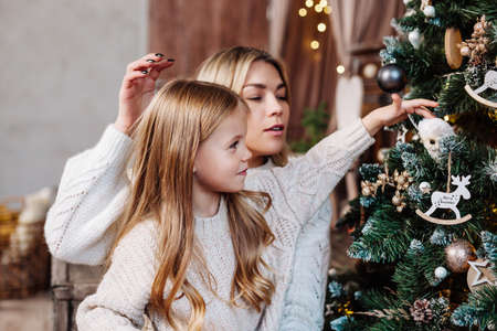 Small cute girl decorating Christmas tree with her motherの写真素材
