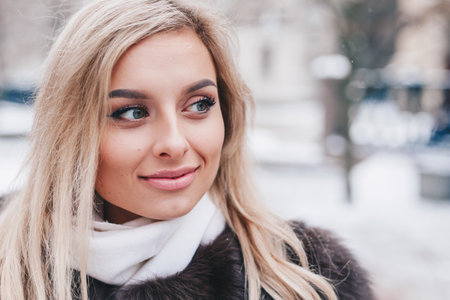 Young beautiful smiling girl wearing fur winter coat looking awayの写真素材