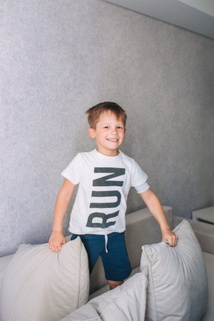 little boy having pillow fight on sofa at home