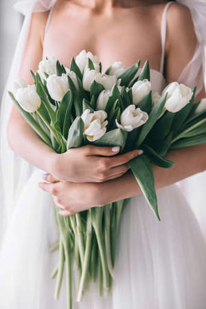 Wedding bouquet of white tulips in the hands of a beautiful bride indoor. Selective Focusの写真素材