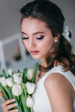 Beautiful bride holding wedding bouquet of white tulips in her hands in studio. Wediing dayの写真素材