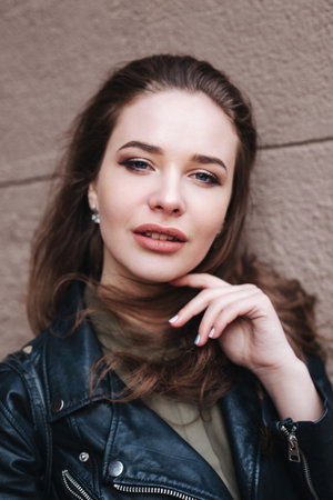 Close-up portrait of young stylish woman with curly hair looking at cameraの写真素材