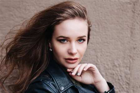 Close-up portrait of young woman with curly hair looking at camera in the cityの写真素材