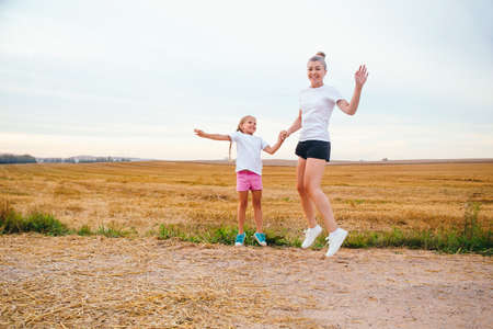 Happy active family in white t-shirt jumping outdoorの写真素材
