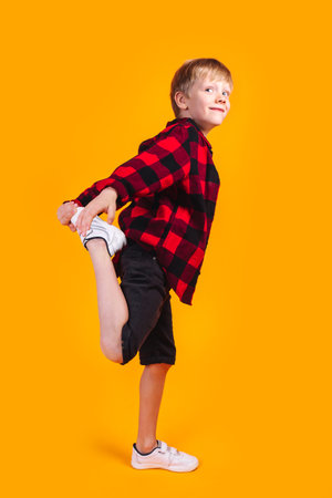 Stylish blond boy kid in a plaid shirt having fun on yellow backgroundの写真素材