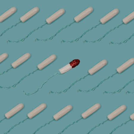 Menstrual period concept. Patern made of cotton tampons with red gliter on blue background. Woman hygiene protection. Feminist art.の写真素材