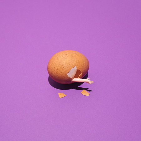Creative idea of salvation.  Broken egg with a hand on purple background. Surreal concept.の写真素材