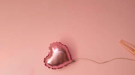 Pink balloon in a shape of heart on pale rose background. Creative concept for Valentine's day and Woman's day.の写真素材