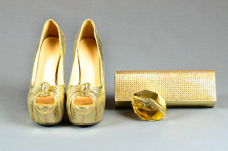 Gold high-heeled shoes, clutch bag and perfume on a gray backgroundの写真素材