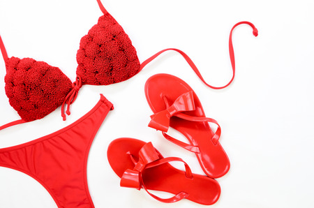 Red bathing suit and red flip-flops on white background. Summer clothes.の写真素材