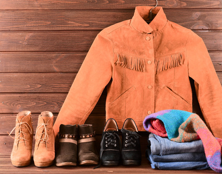 Women's clothing and accessories. Brown suede jacket, jeans, three different pairs of shoes and knitted warm scarfの写真素材
