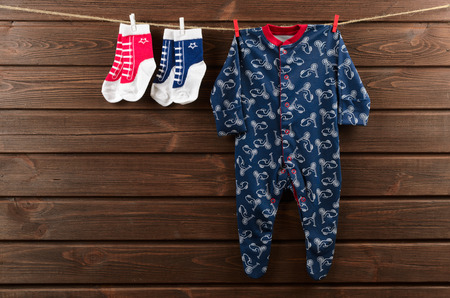 Baby boy clothes (sleepsuit and socks) hanging on the clotheslineの写真素材