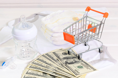 baby accessories  and shopping basket on white wooden background. as concept of baby costsの写真素材