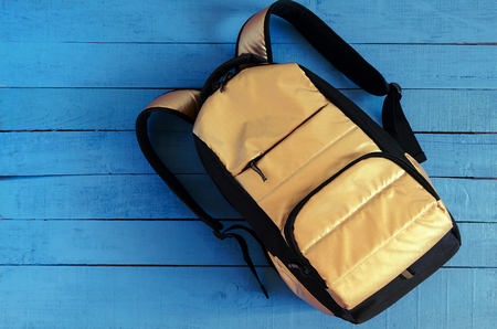 yellow golden backpack on blue wooden backgroundの写真素材
