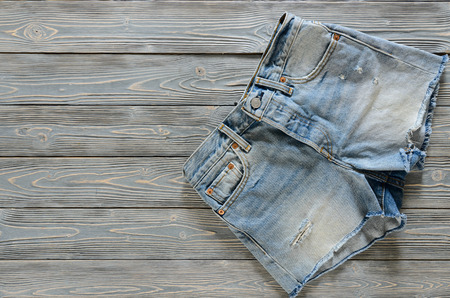 Womens clothing (denim shorts) on grey wooden background with copy space. Trendy fashion outfit. Shopping concept. Mock up for online store.  Flat lay. Summer collectionの写真素材