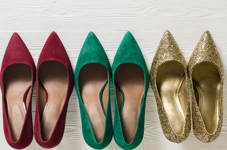 Fashion womens shoes (pumps). Classic christmas colors (red, green, gold). Footwear on white wooden background with copy space. Template for online store, website, banners. Flat lay, top down viewの写真素材