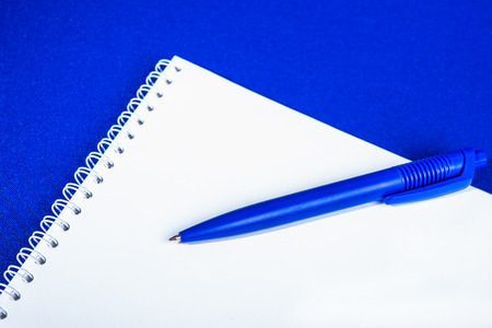 Spiral notebook with pen on blue backgroundの写真素材