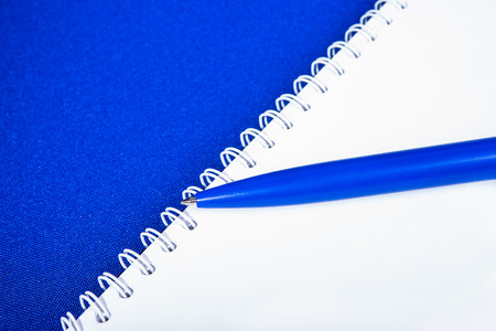 Spiral notebook with pen on blue backgroundの写真素材