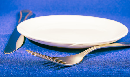knife, fork  and plate at napkin on blue backgroundの写真素材