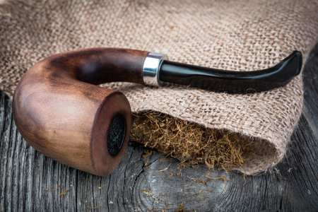 Smoking pipe and tobacco on burlap backgroundの写真素材