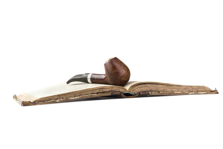 brown tobacco pipe on vintage book  isolated in white background