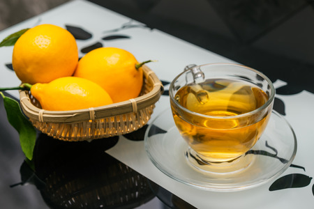 cup of tea and lemons on glass kitchen tableの写真素材
