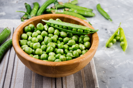 Green pea in wooden bowl on rustic wooden tableの写真素材