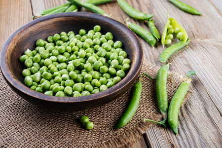 Green pea in wooden bowl on rustic wooden tableの写真素材
