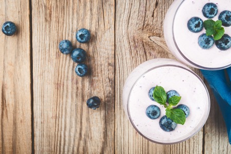 Smoothie or milkshake with  blueberries  in a glasses on rustic wooden  table, top viewの写真素材