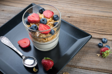 Fresh yogurt with muesli and berries on a wooden table, healthy breakfast
