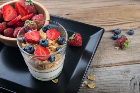 Fresh yogurt with muesli and berries on a wooden table, healthy breakfastの写真素材