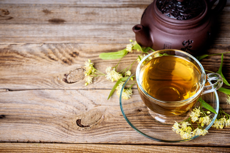 cup of  linden tea and teapot on wooden tableの写真素材