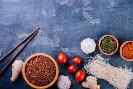 Raw rice noodles with spices on dark background.Top view. Copy space. Healthy vegetarian food concept.の写真素材