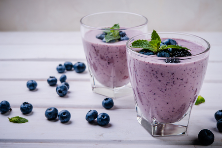 healthy smoothie or shake with fresh blueberries on a white wooden  backgroundの写真素材