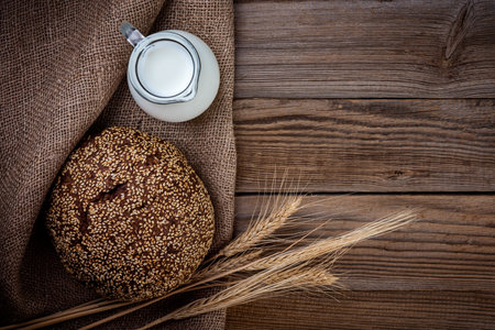 Fresh bread and wheat on burlap at an  rustic wood table, top view