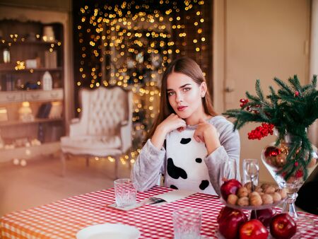 Smiling beautiful woman sitting at home near christmas treeの写真素材