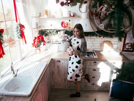 Smiling beautiful woman sitting at home near christmas treeの写真素材