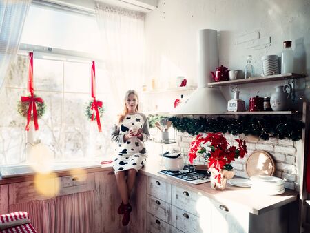 Smiling beautiful woman sitting at home near christmas treeの写真素材