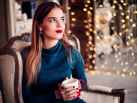 Smiling beautiful woman sitting at home near christmas treeの写真素材